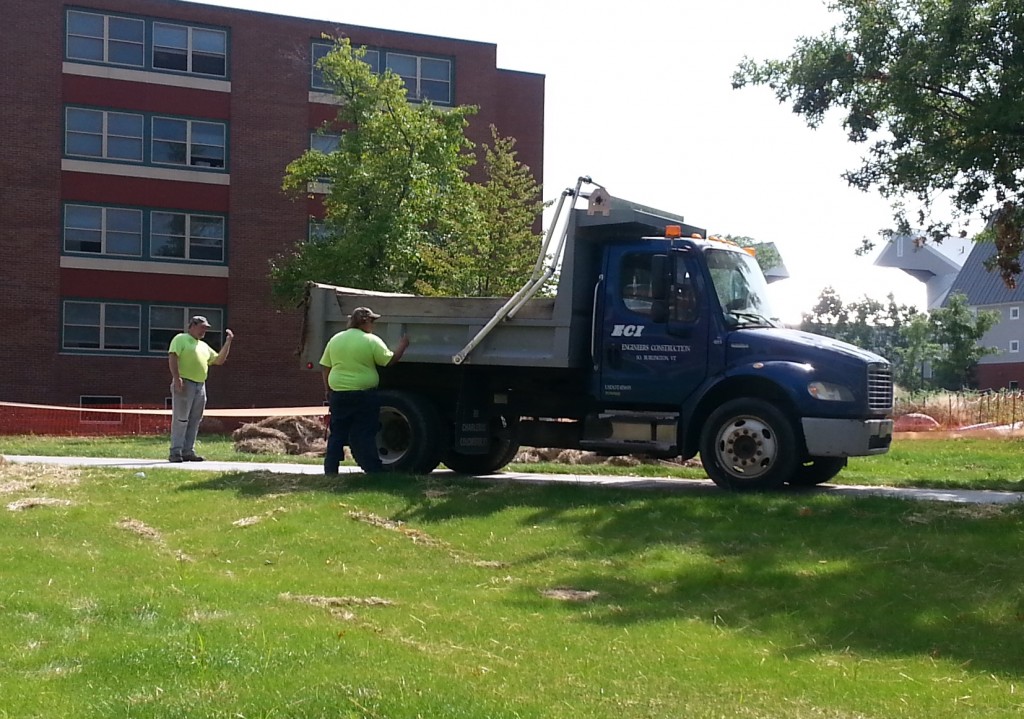 Two ECI spotters direct a truck making a reverse movement on the busy UVM Campus
